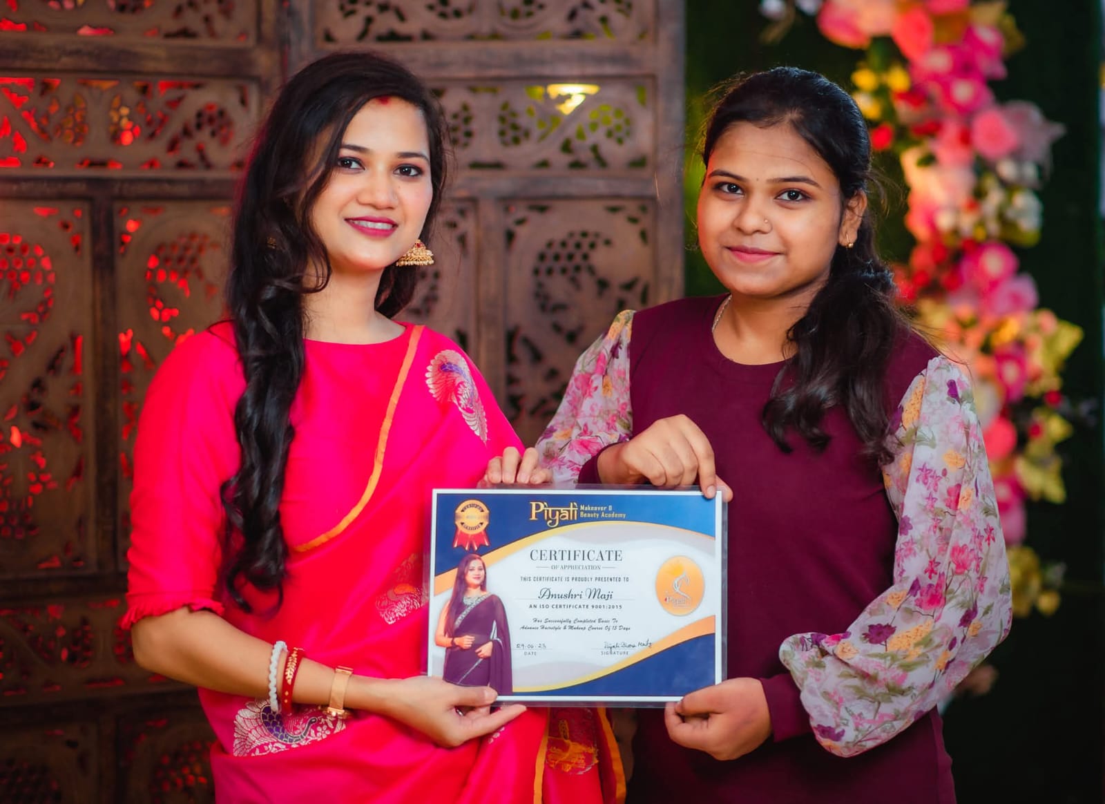 Student receiving her Pearl Beauty Salon & Academy certificate of appreciation from the founder in front of the salon logo