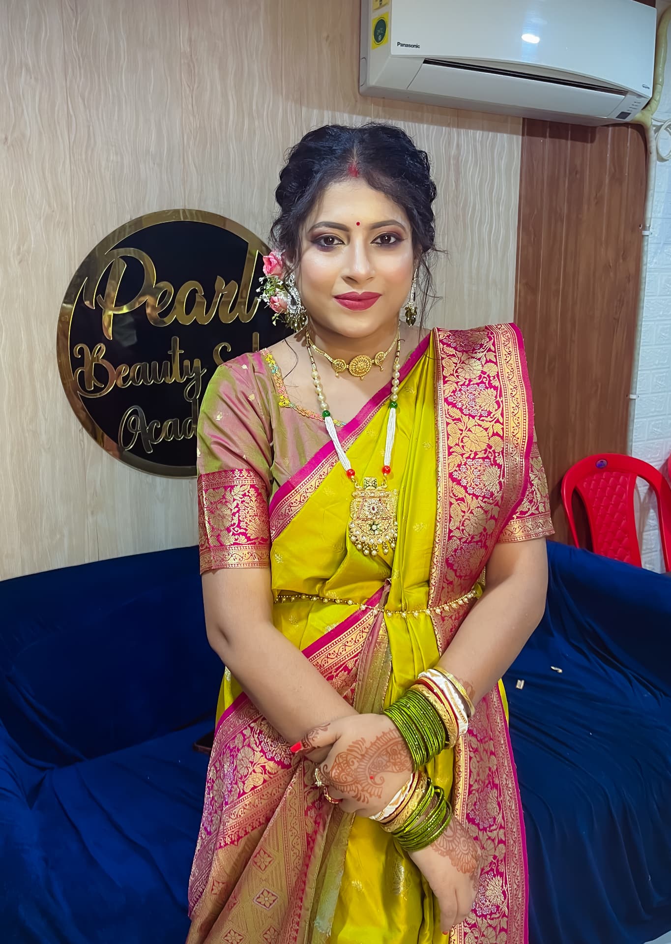 Bride in a yellow and pink benarasi sari with fresh flowers in her hair and traditional gold jewellery
